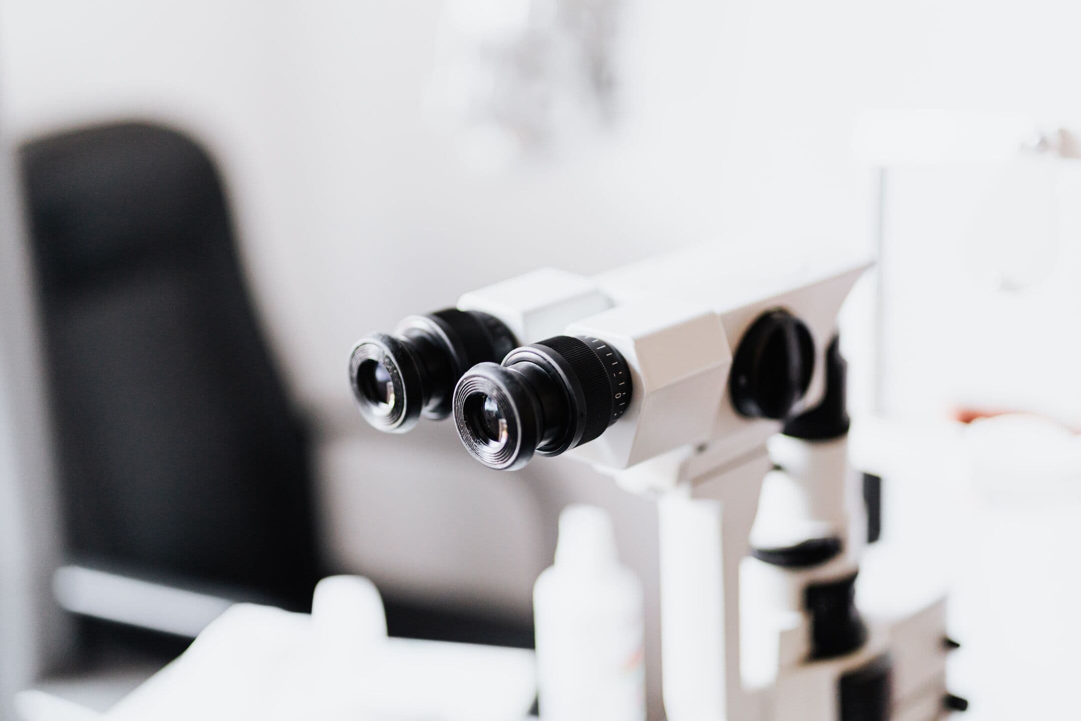 The eyepieces of a slit lamp, an eye examination microscope, in a bright exam room with no one in it