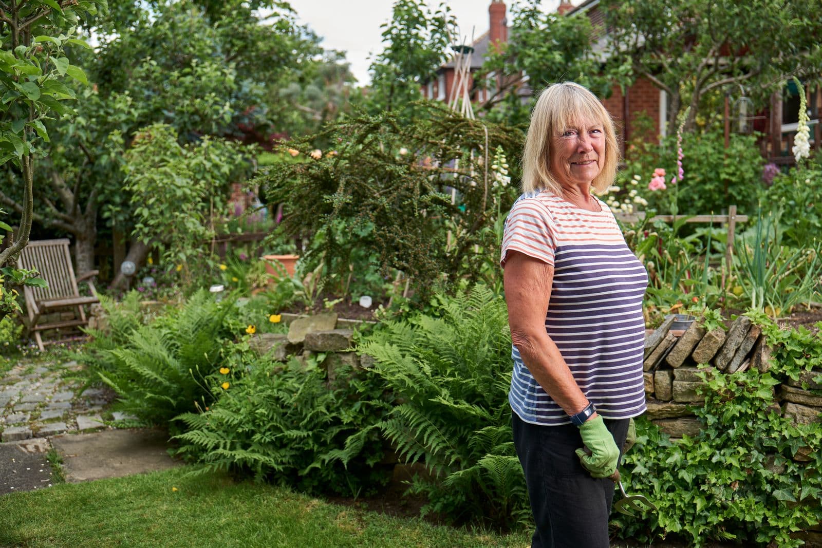 Smiling senior woman standing in a lush green garden
