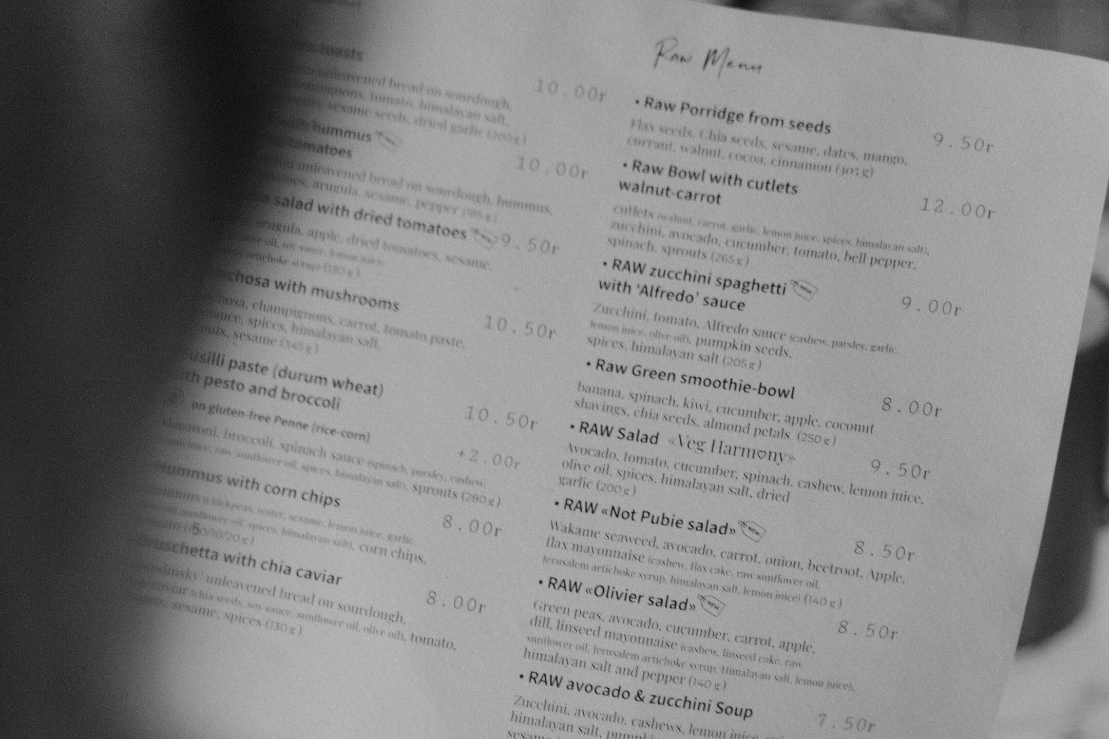 A printed restaurant menu held out at a distance, in black and white